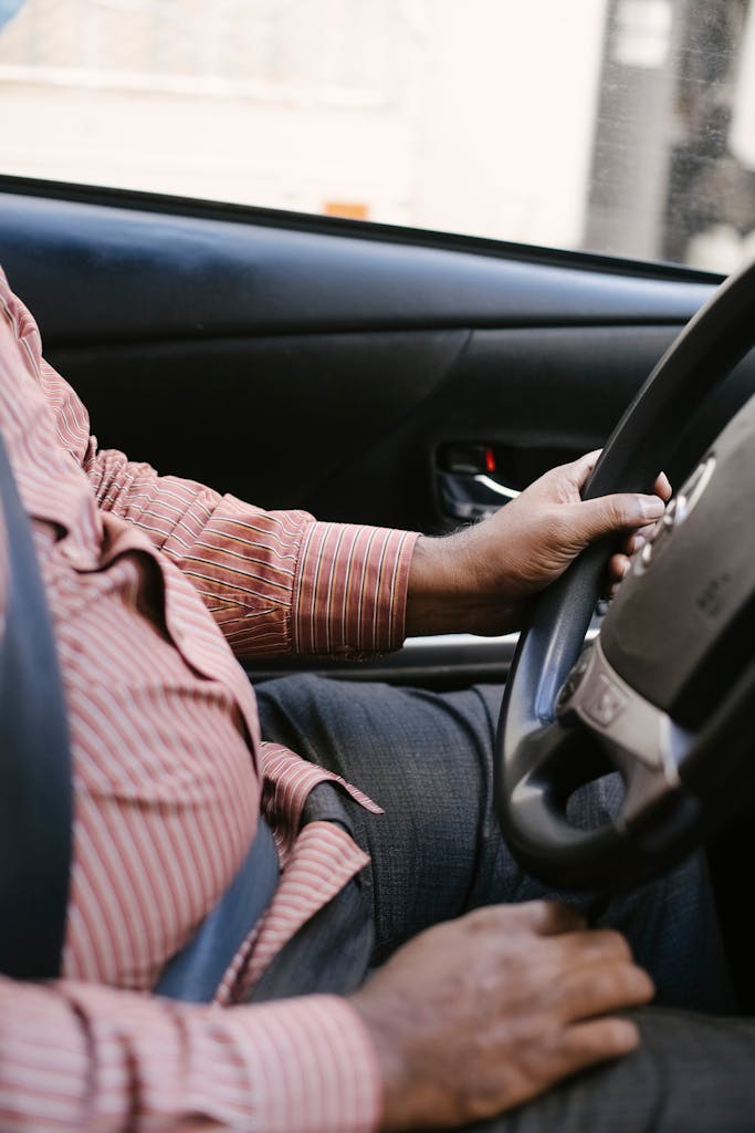 Side view of crop anonymous ethnic man in casual wear with ornament driving transport in daylight